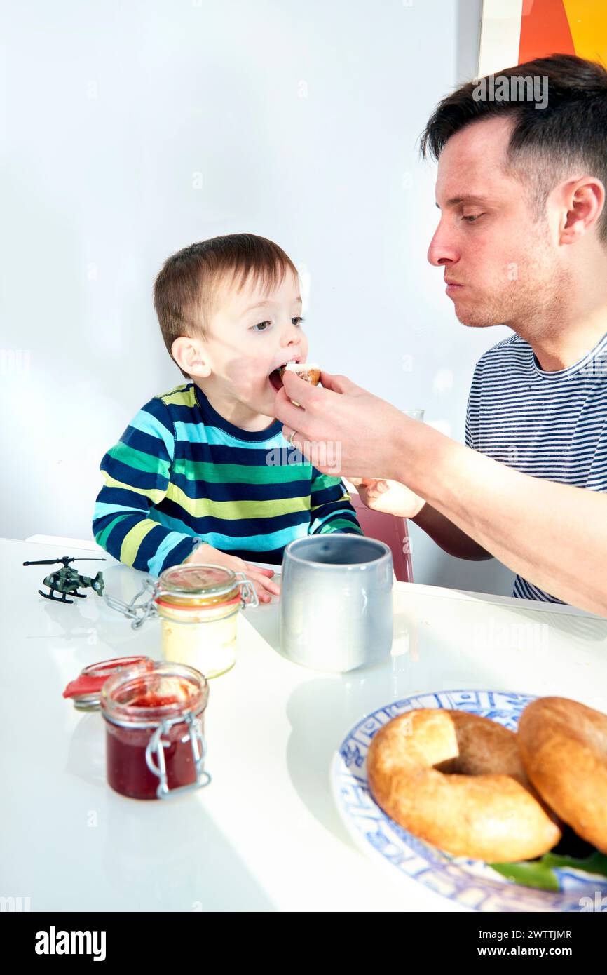 Vater füttert ein kleines Kind am Tisch Stockfoto