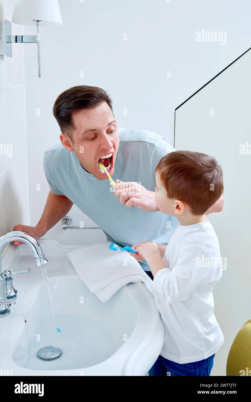 Das Kind hilft Erwachsenen beim Zähneputzen im Badezimmer Stockfoto