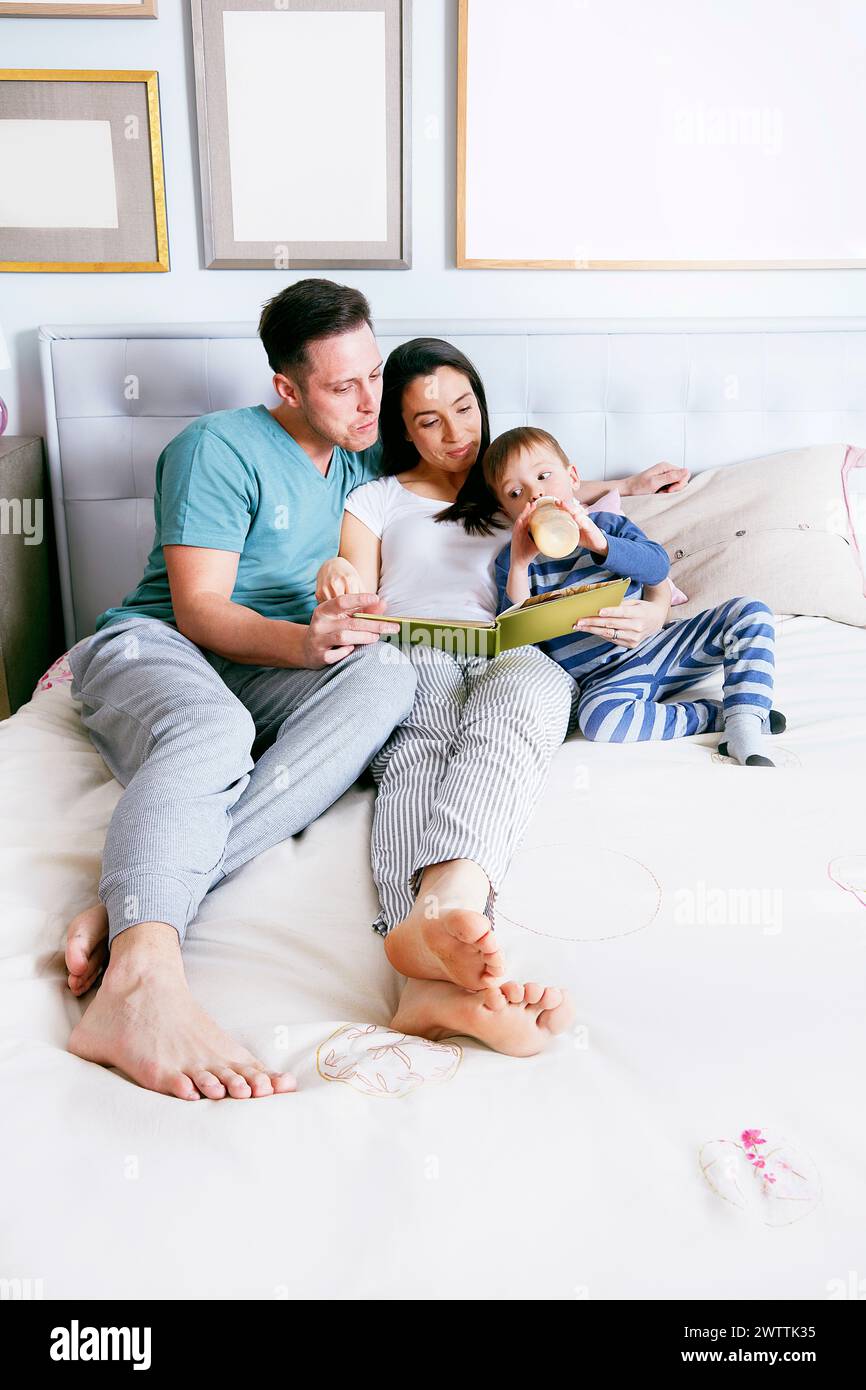 Familie liest zusammen ein Buch auf einem Bett Stockfoto