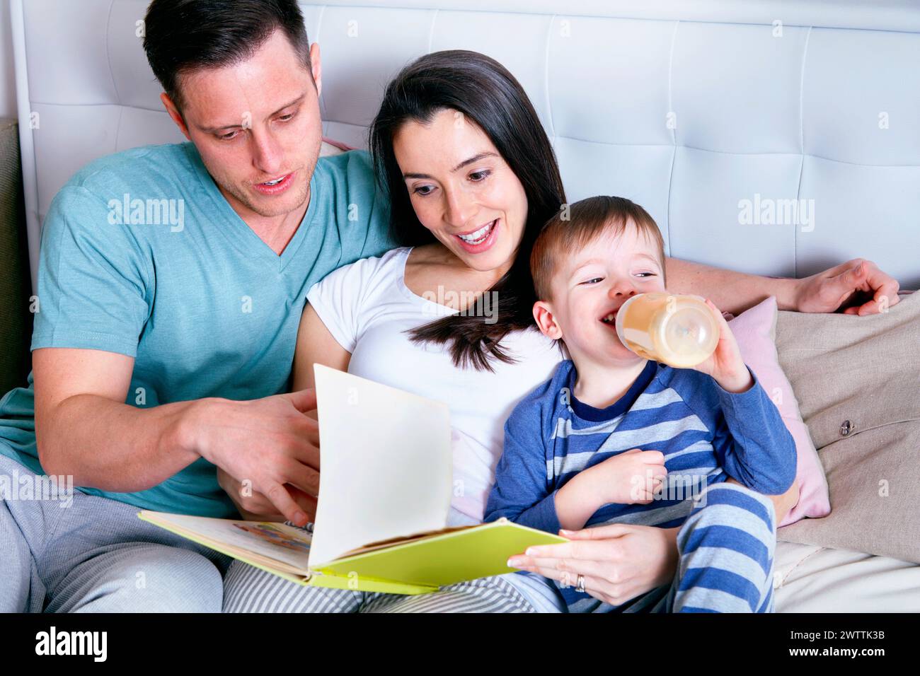 Familie liest ein Buch zusammen auf einer Couch Stockfoto