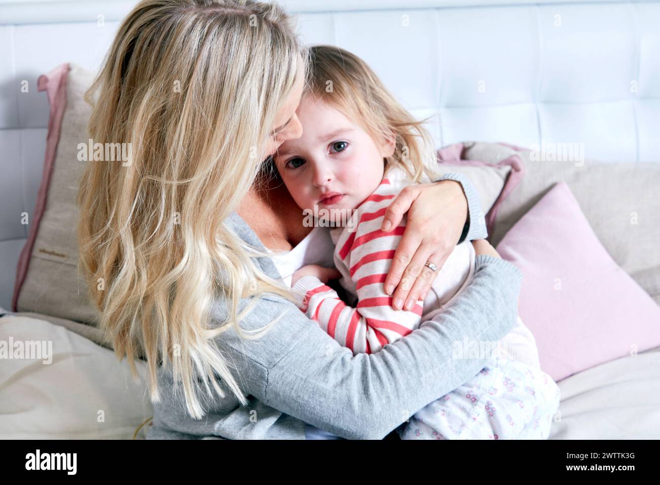 Mutter tröstet ihr trauriges Kind auf einem Bett Stockfoto