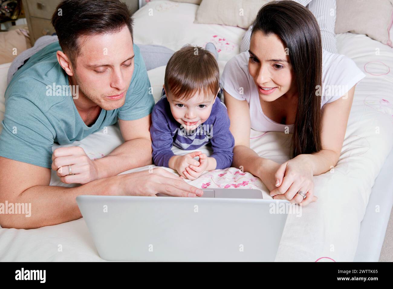 Familie, die einen Laptop auf einem Bett benutzt. Stockfoto