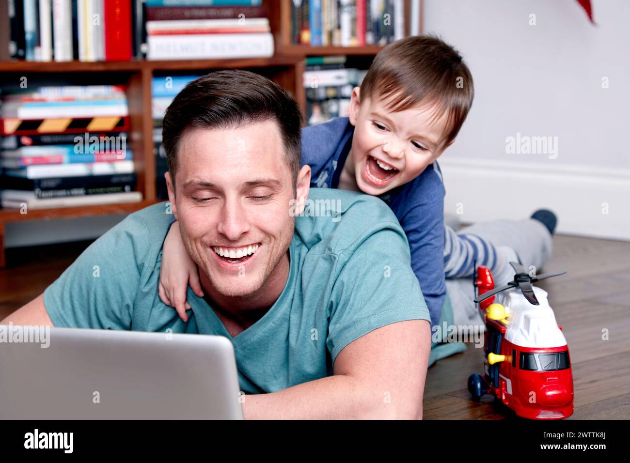 Vater und Sohn genießen die Zeit zusammen mit einem Laptop und Spielzeug Stockfoto