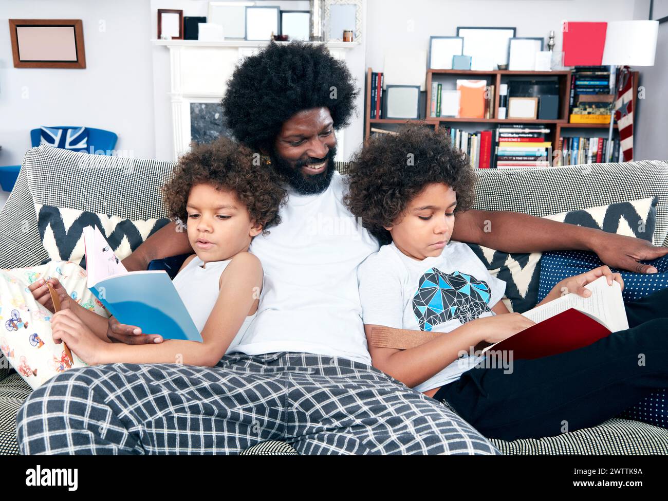 Familie liest Bücher zusammen auf einer Couch. Stockfoto