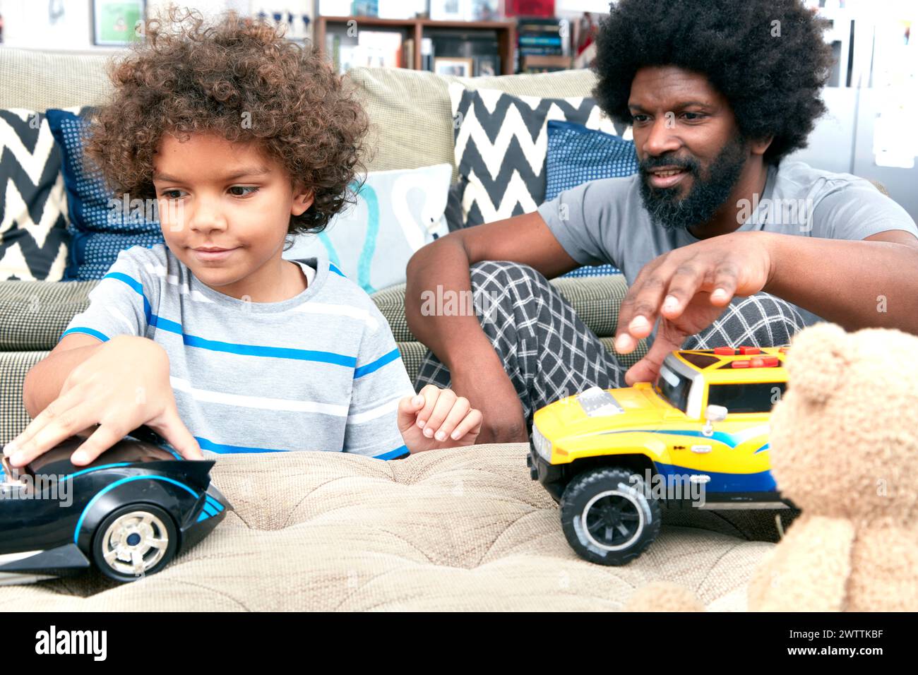 Vater und Kind spielen mit Spielzeugautos auf einer Couch Stockfoto