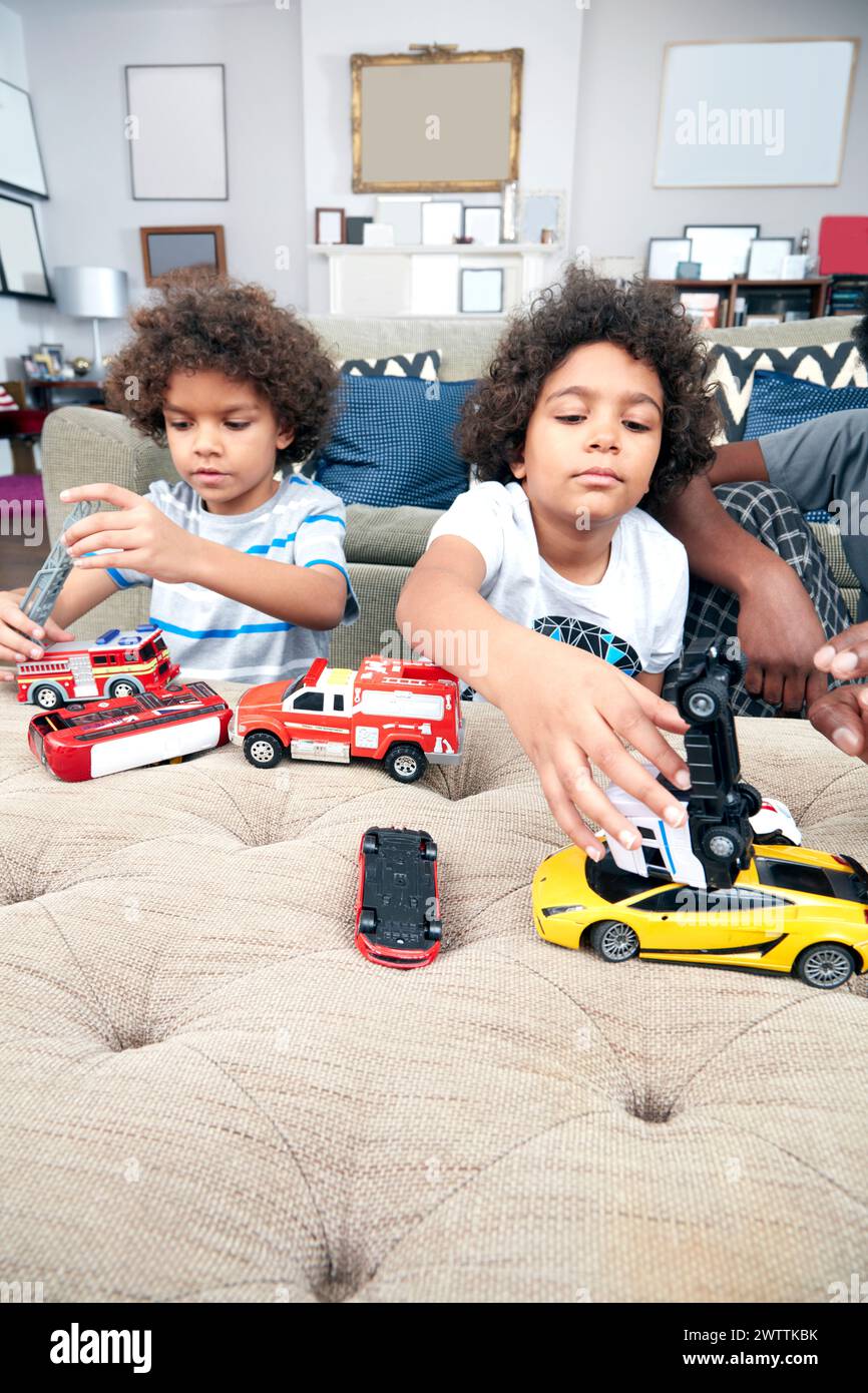 Kinder, die mit Spielzeugautos auf einem Sofa spielen Stockfoto