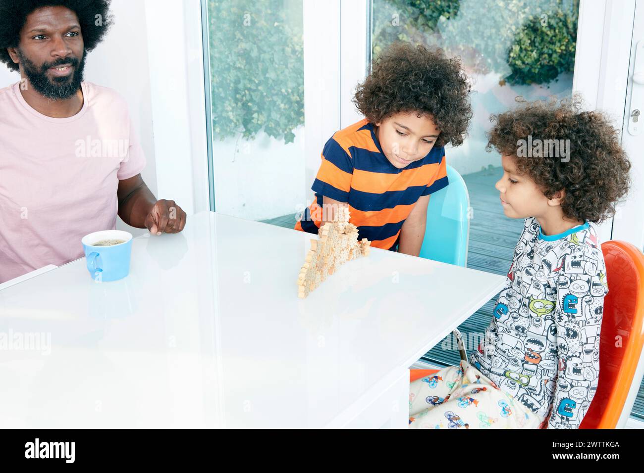Familie genießt gemeinsame Zeit an einem weißen Tisch Stockfoto