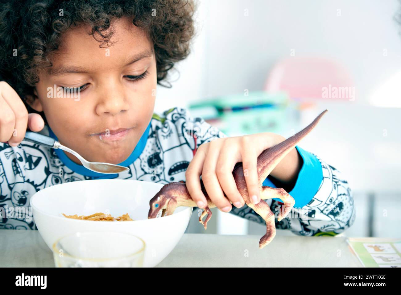 Kind spielt mit Spielzeug-Dinosaurier zu den Mahlzeiten Stockfoto