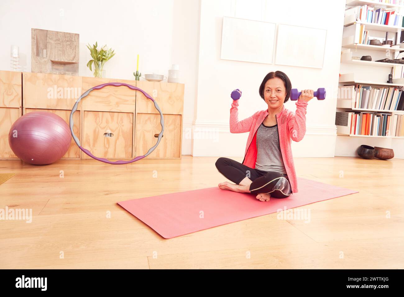 Frau, die zu Hause mit Kurzhanteln auf einer Yogamatte trainiert Stockfoto