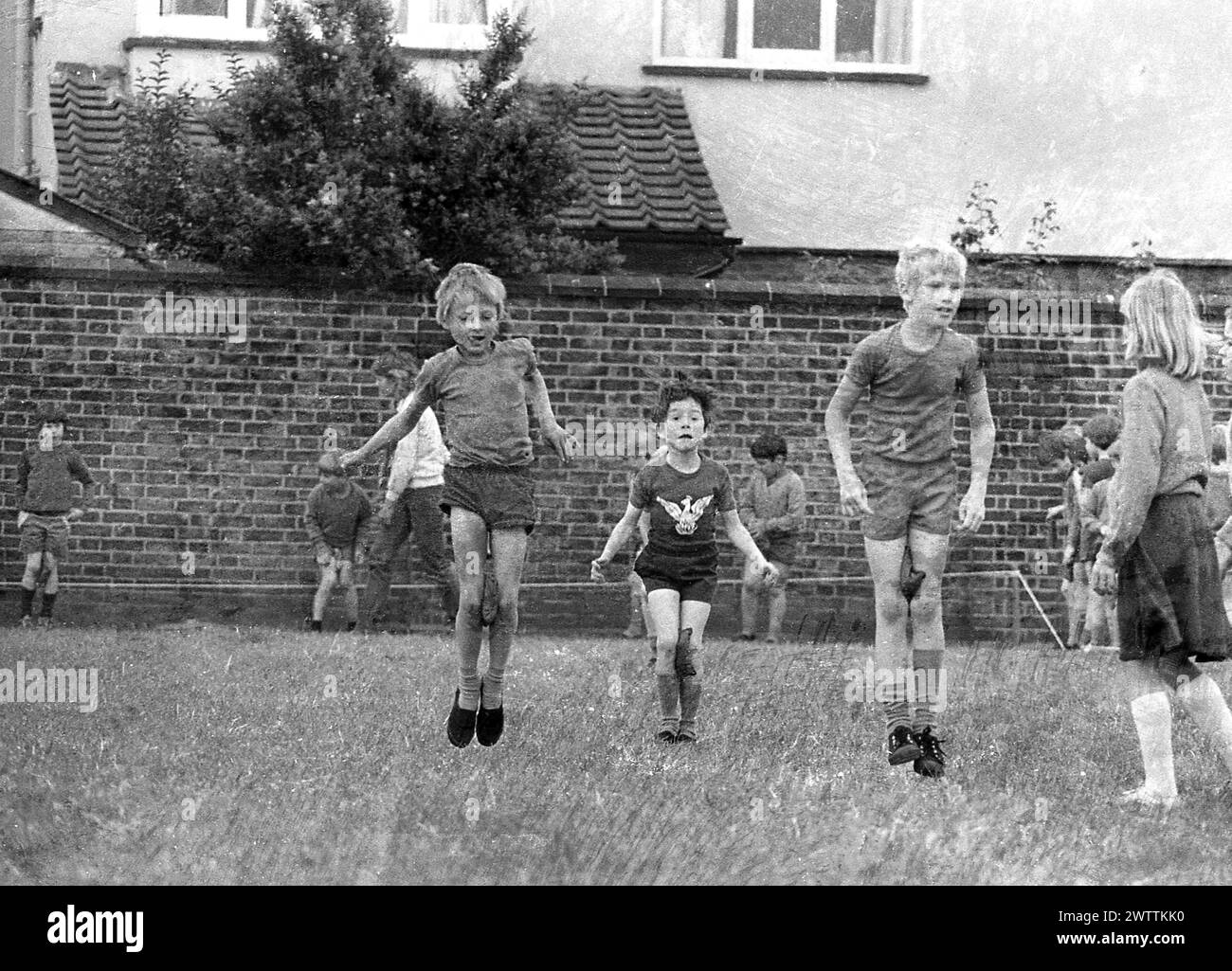 1970er Jahre, historische Grundschulsportarten, draußen auf einem Grasfeld, kleine Kinder, die an einem Springrennen mit einem Schwamm zwischen den Knien teilnehmen, England, Großbritannien. Stockfoto