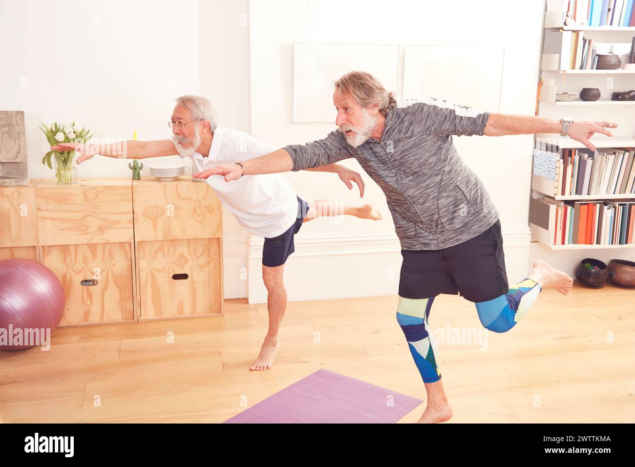 Zwei Leute üben Yoga in einem hellen Raum. Stockfoto