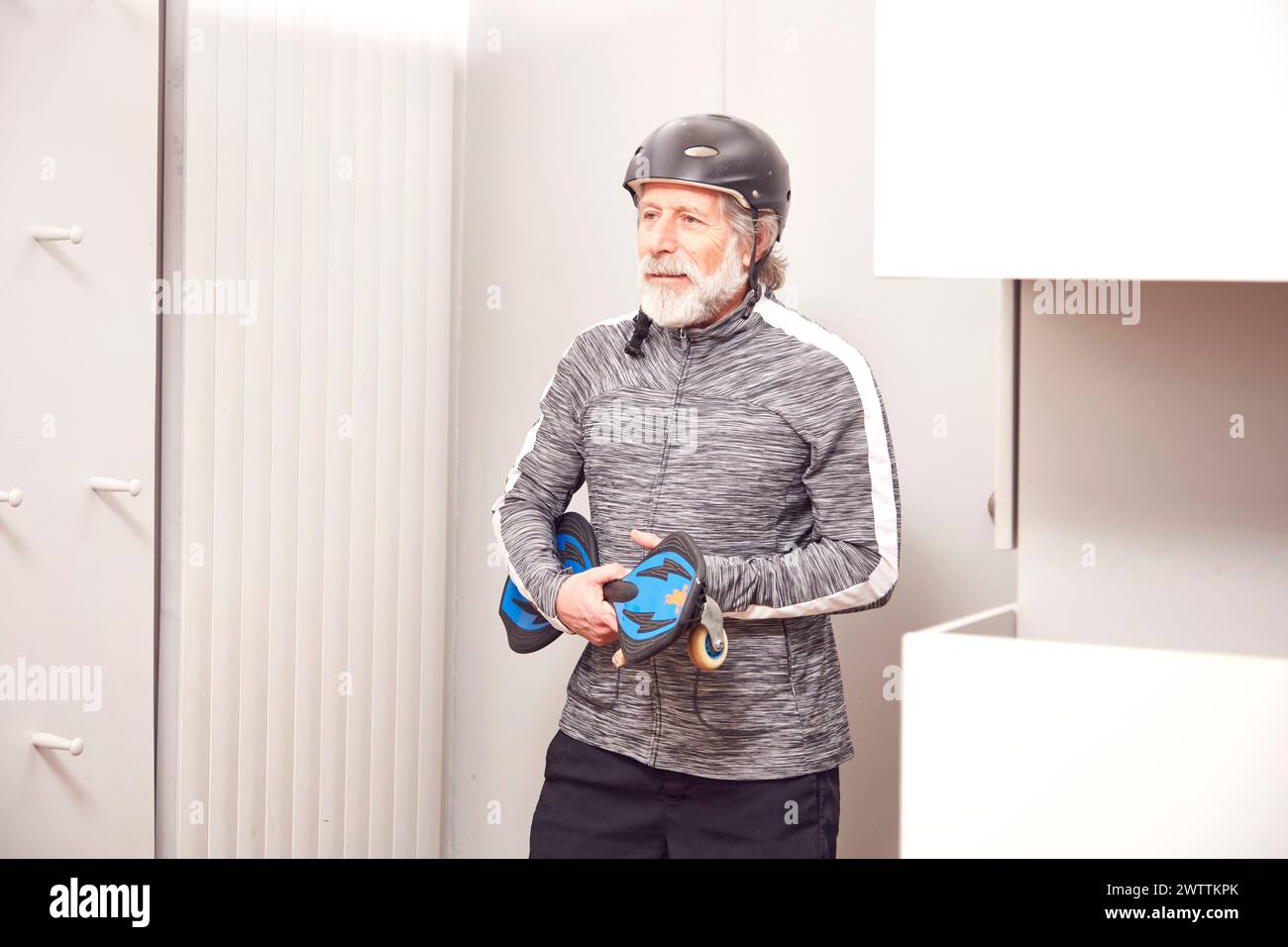 Senior Mann mit Fahrradhelm und Handschuhen in einem Raum. Stockfoto