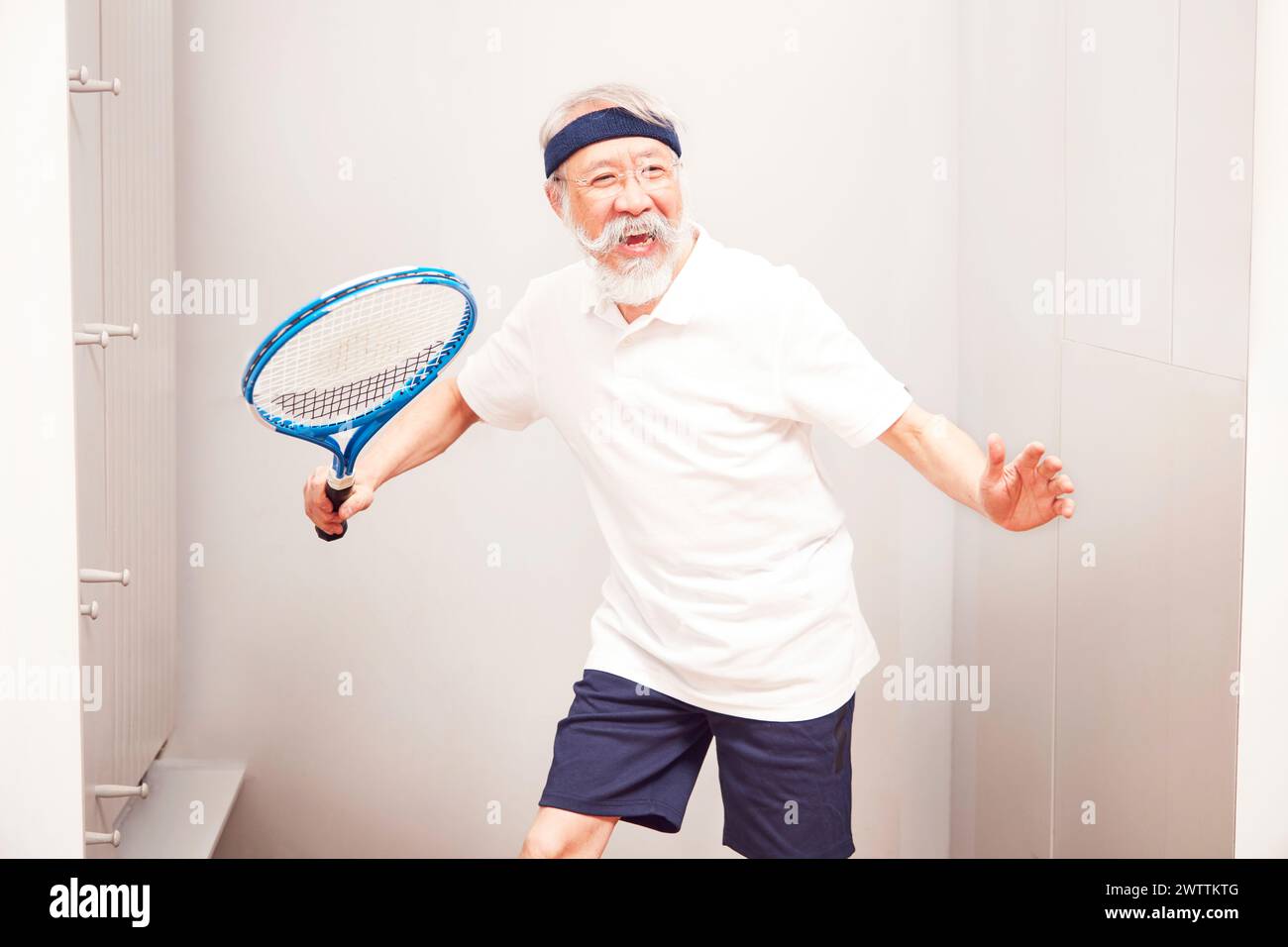 Ein älterer Mann posiert mit einem Tennisschläger. Stockfoto
