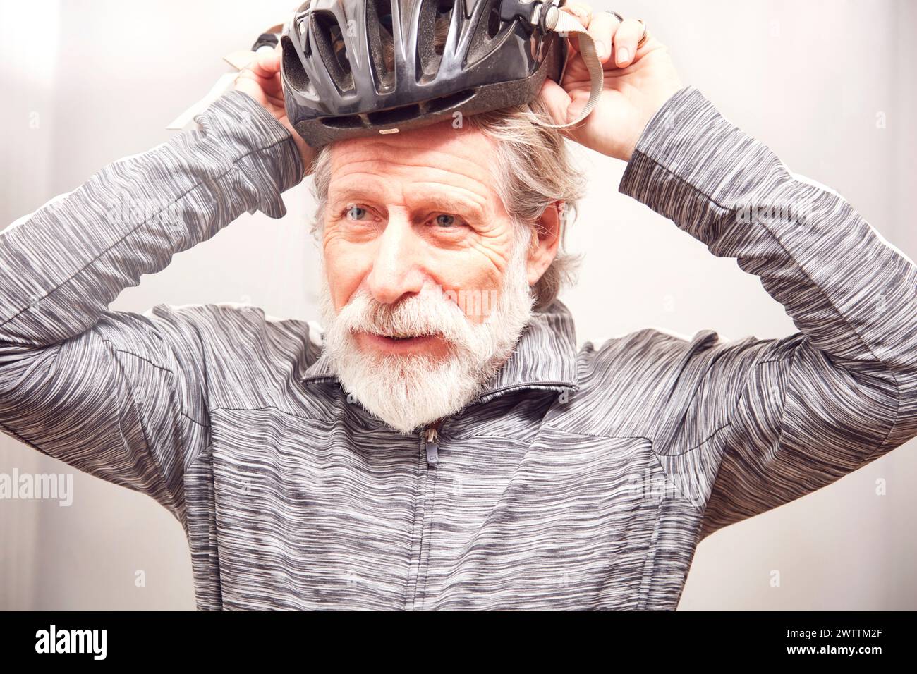 Senior-Mann, der einen Fahrradhelm aufsetzt. Stockfoto