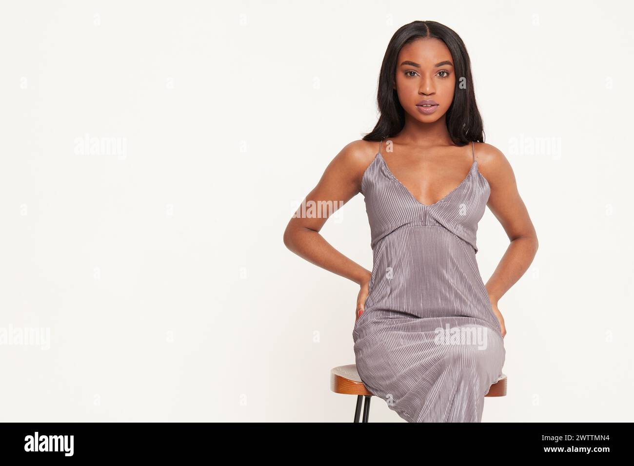 Frau posiert in einem grauen Kleid auf weißem Hintergrund Stockfoto