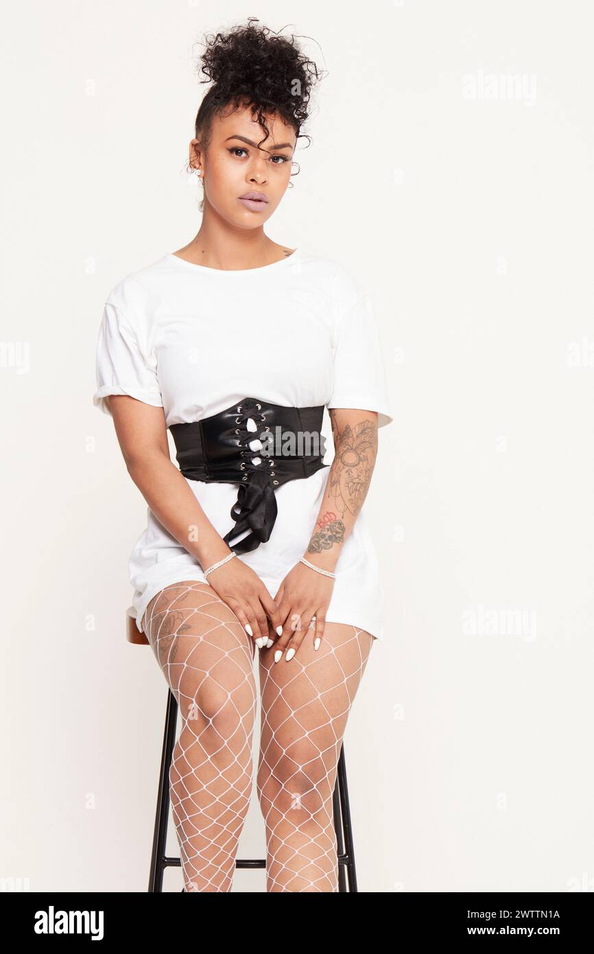 Frau sitzt auf einem Hocker in stilvollem Outfit Stockfoto