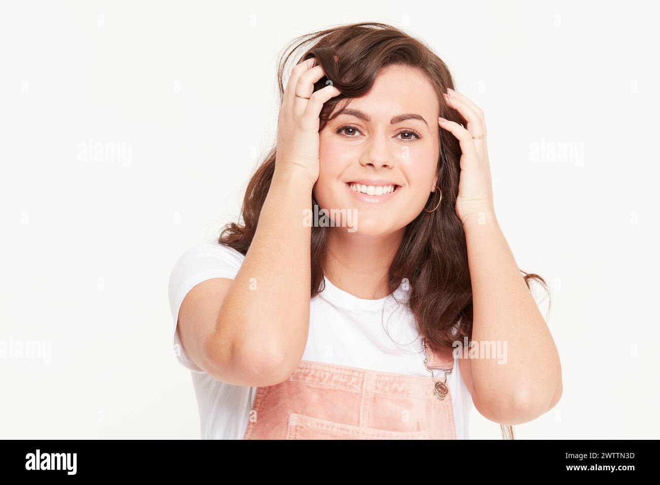 Lächelnde Frau posiert mit Händen im Haar Stockfoto