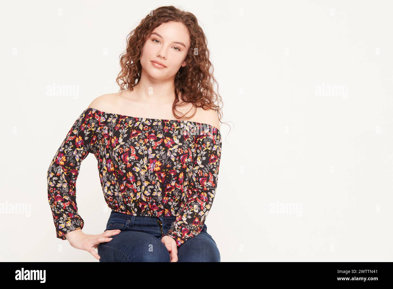 Frau posiert in schulterfreiem Oberteil und Jeans Stockfoto