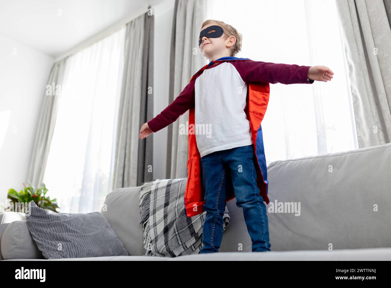 Kind im Superheldenkostüm, das zu Hause spielt Stockfoto