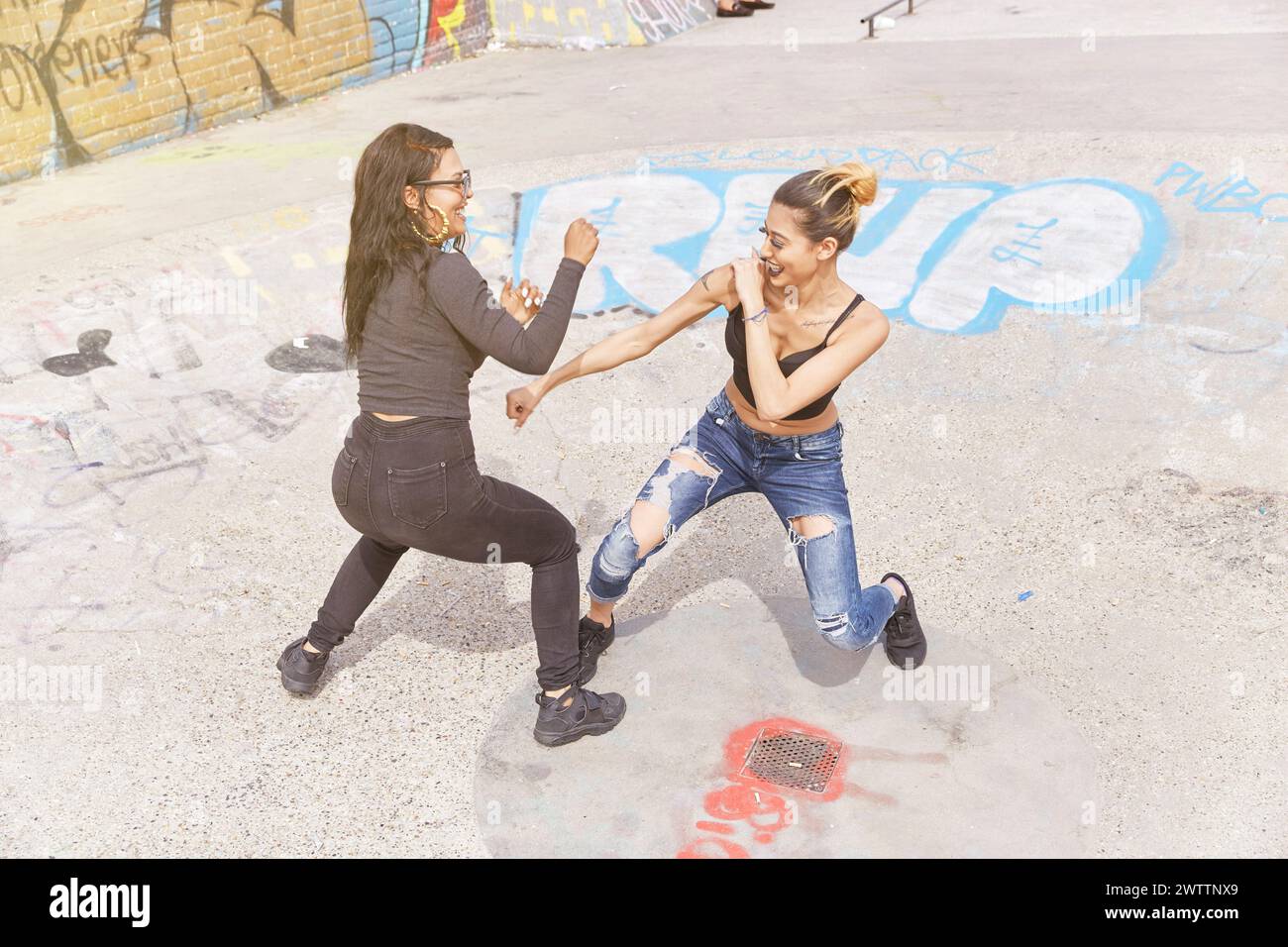 Zwei Frauen tanzen auf einer mit Graffiti bedeckten Straße Stockfoto