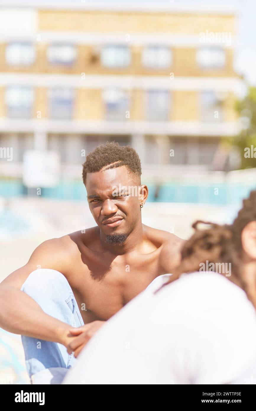 Junger Mann, der draußen im Gespräch sitzt Stockfoto