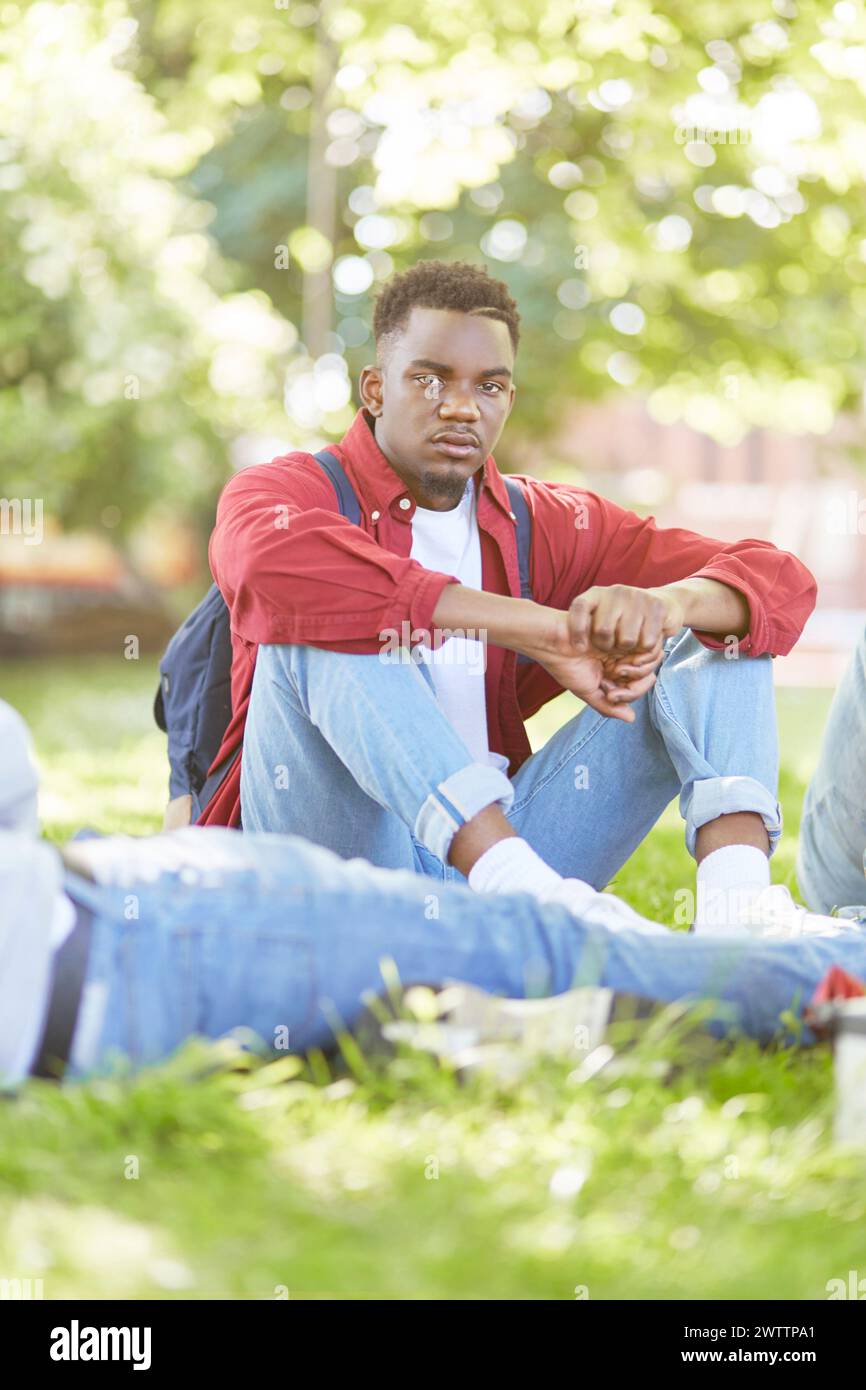 Junger Mann, der draußen in einem Park sitzt Stockfoto