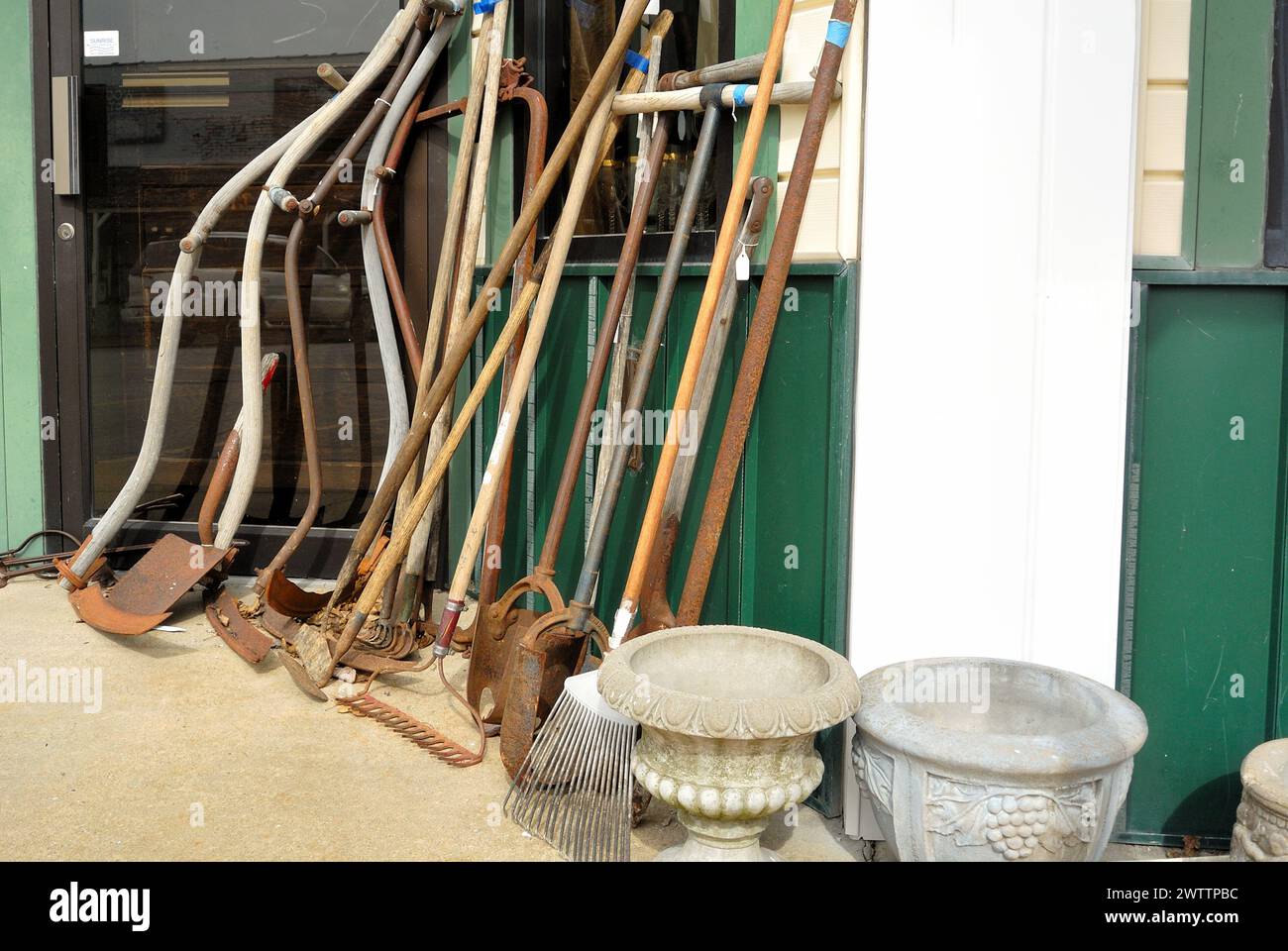Alte Farm Crop Tools auf dem Gehweg vor dem Antiquitätenladen. Stockfoto