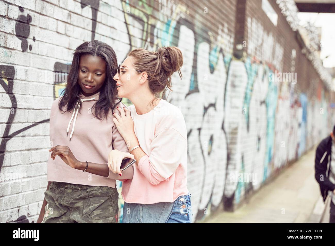 Zwei Frauen, die sich an einer Graffiti-Wand unterhalten Stockfoto