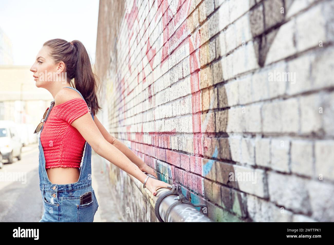 Frau, die sich an einem Geländer an einer Graffiti-Wand lehnt Stockfoto