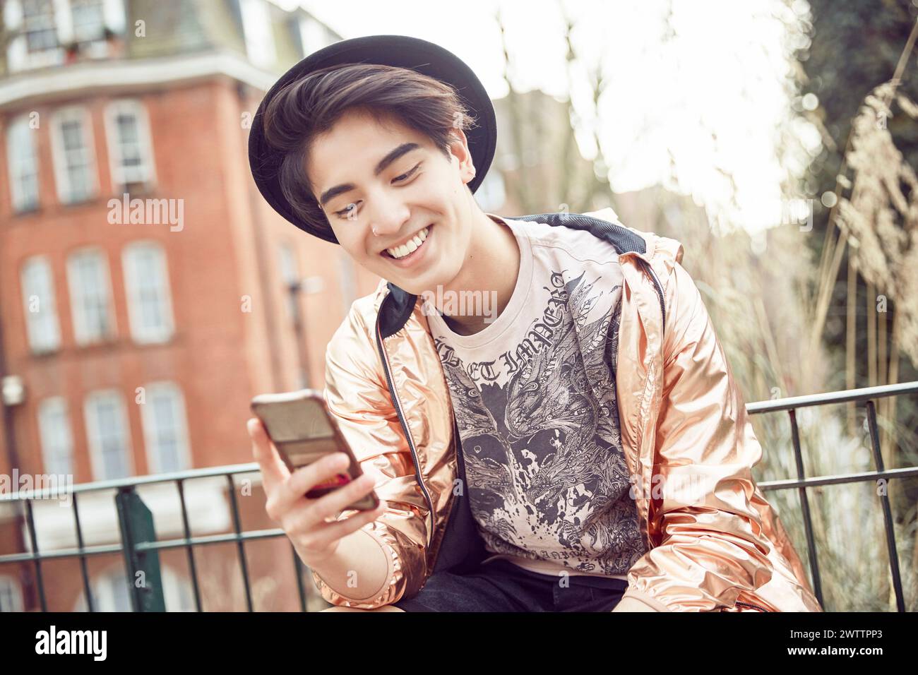 Junge Person lächelt am Telefon in urbaner Umgebung Stockfoto