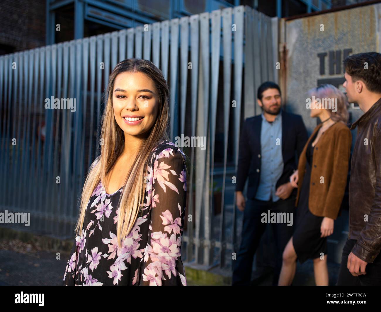 Frau lächelt im Vordergrund mit Leuten im Hintergrund Stockfoto
