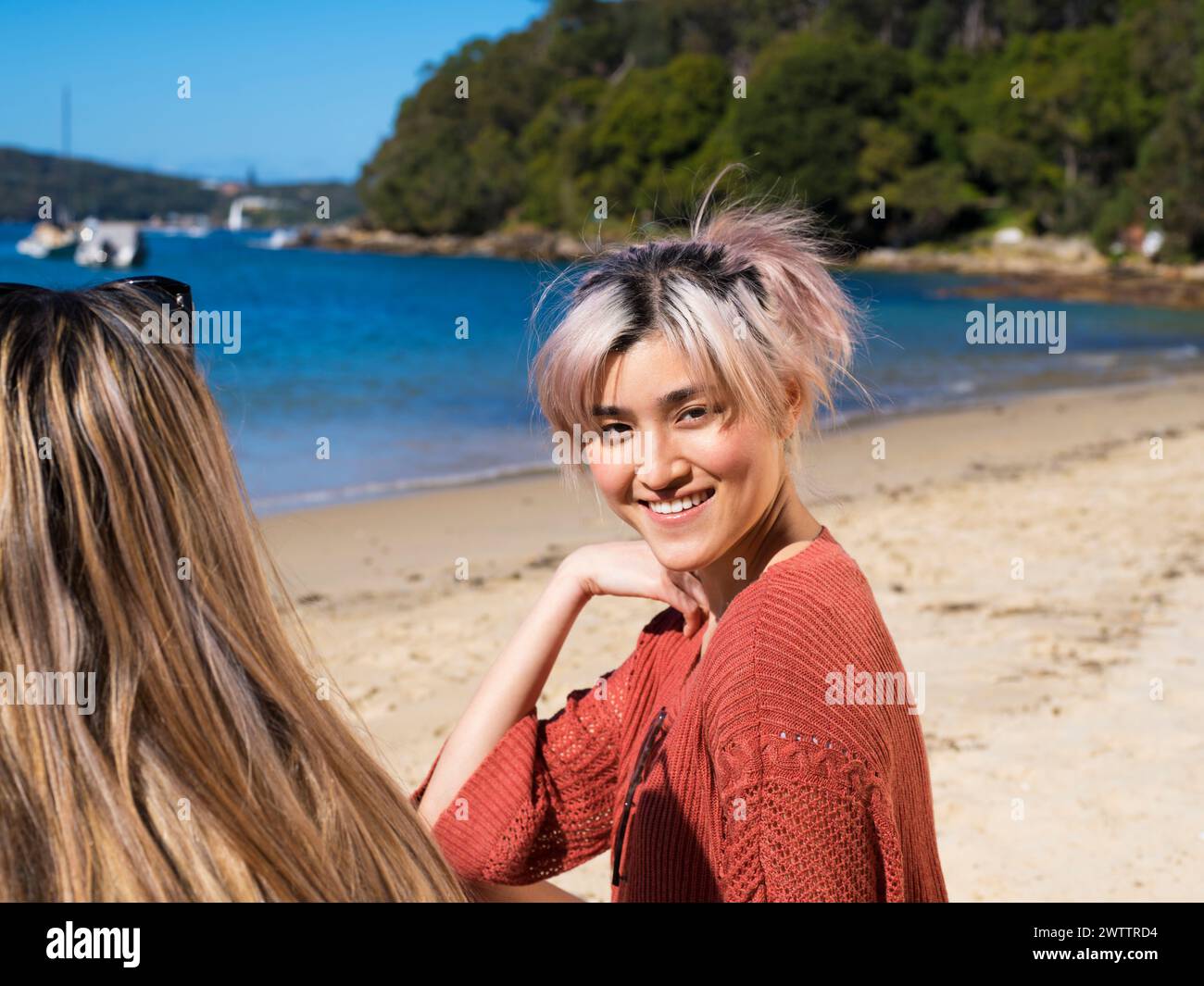 Lächelnde Frau mit rosa Haaren an einem sonnigen Strand Stockfoto