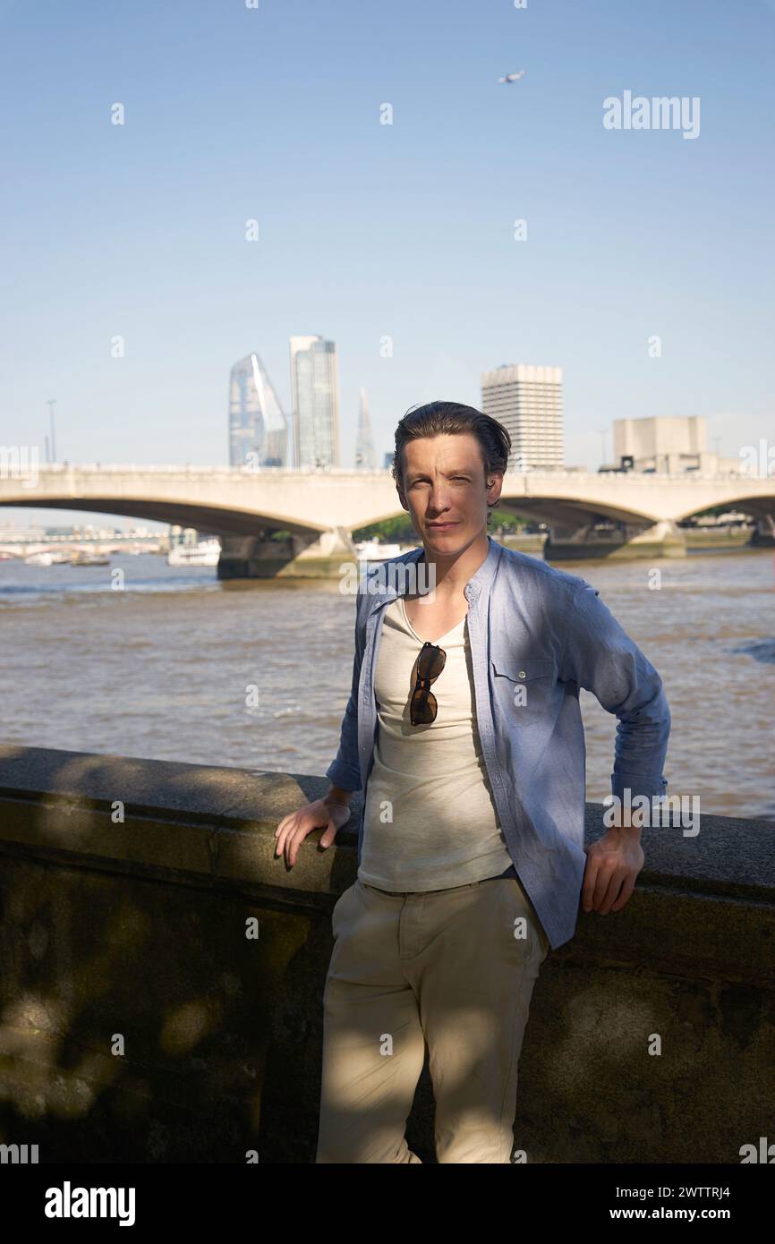Person posiert vor einem Fluss mit einer Skyline der Stadt Stockfoto