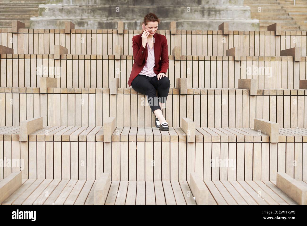 Frau, die auf geometrischen Holzbänken sitzt Stockfoto