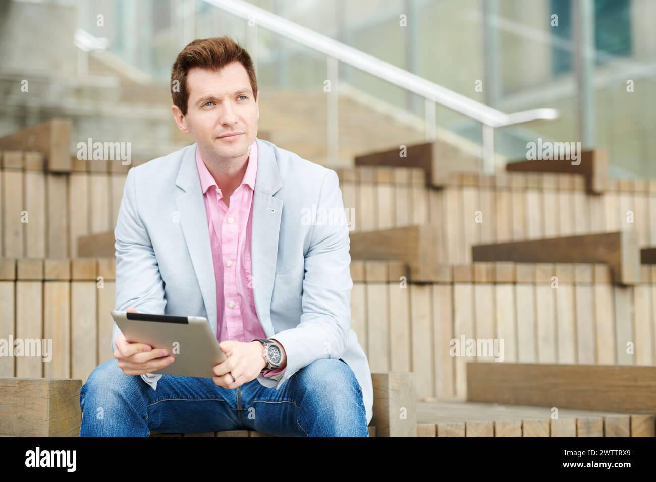 Mann, der mit einem Tablet auf Stufen sitzt Stockfoto