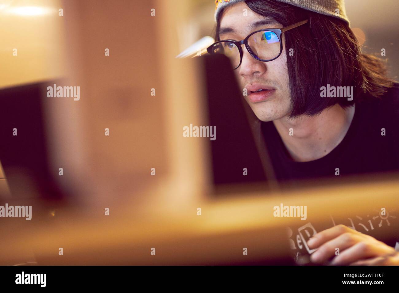 Junge Person, die sich auf Computerarbeit konzentriert Stockfoto