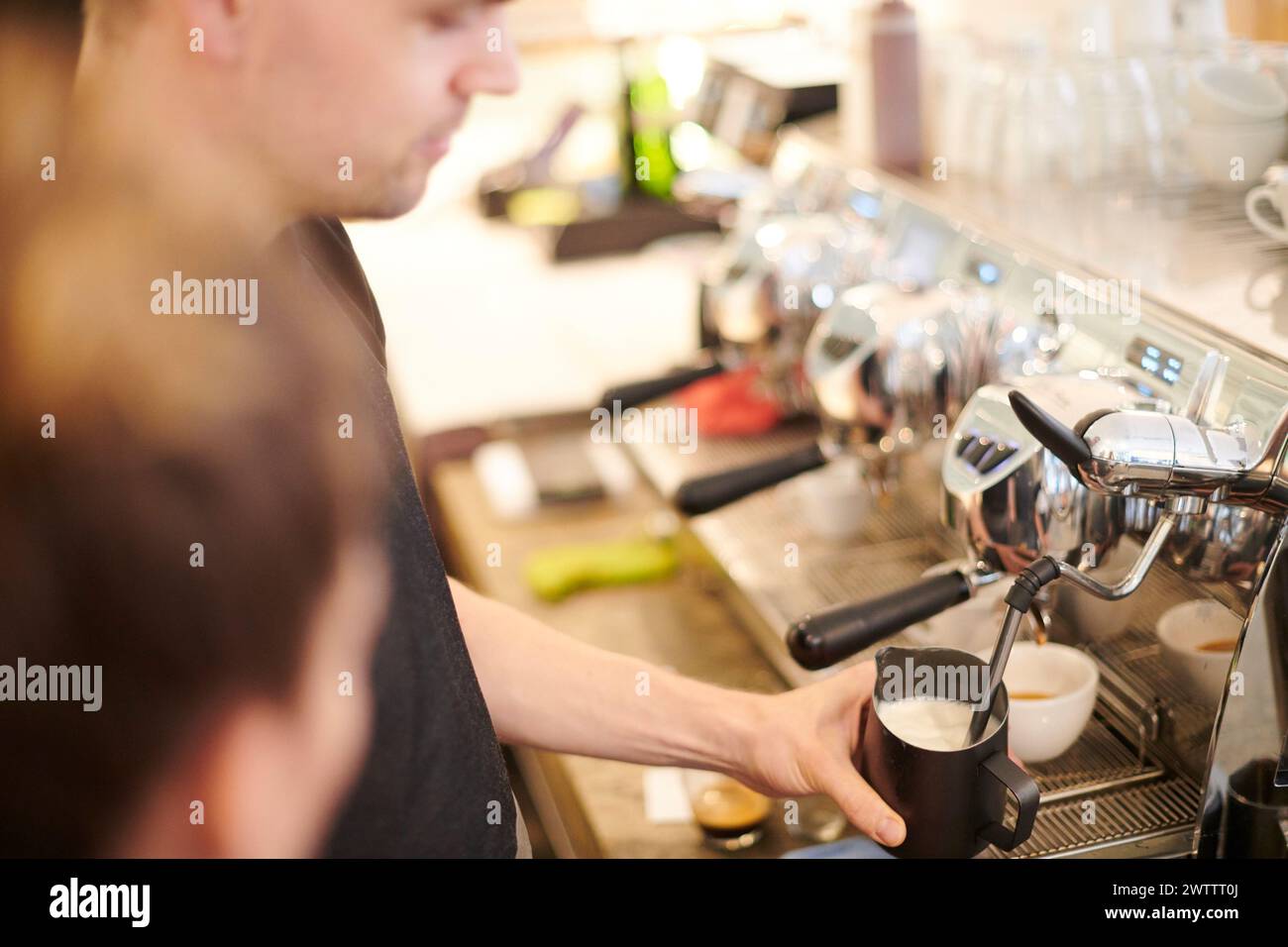 Der Barista schäumt Milch an einer Kaffeemaschine auf Stockfoto