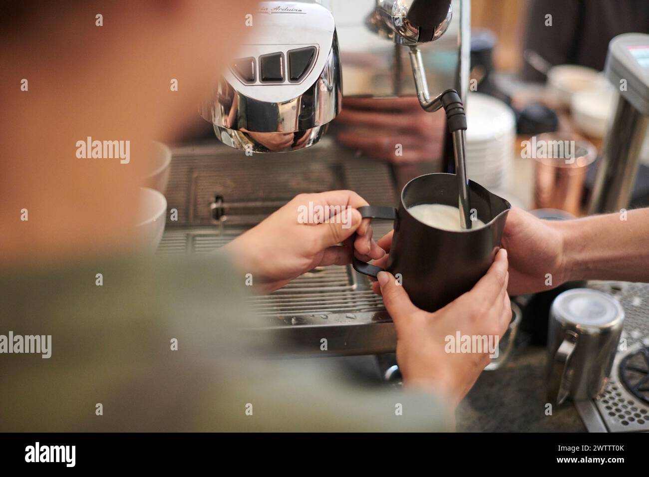 Der Barista schäumt Milch an einer Kaffeemaschine auf. Stockfoto
