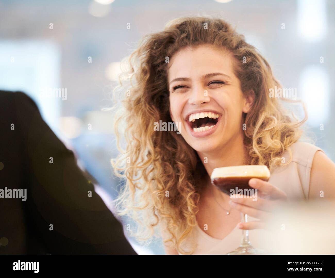 Frau lacht mit einem Drink in der Hand Stockfoto