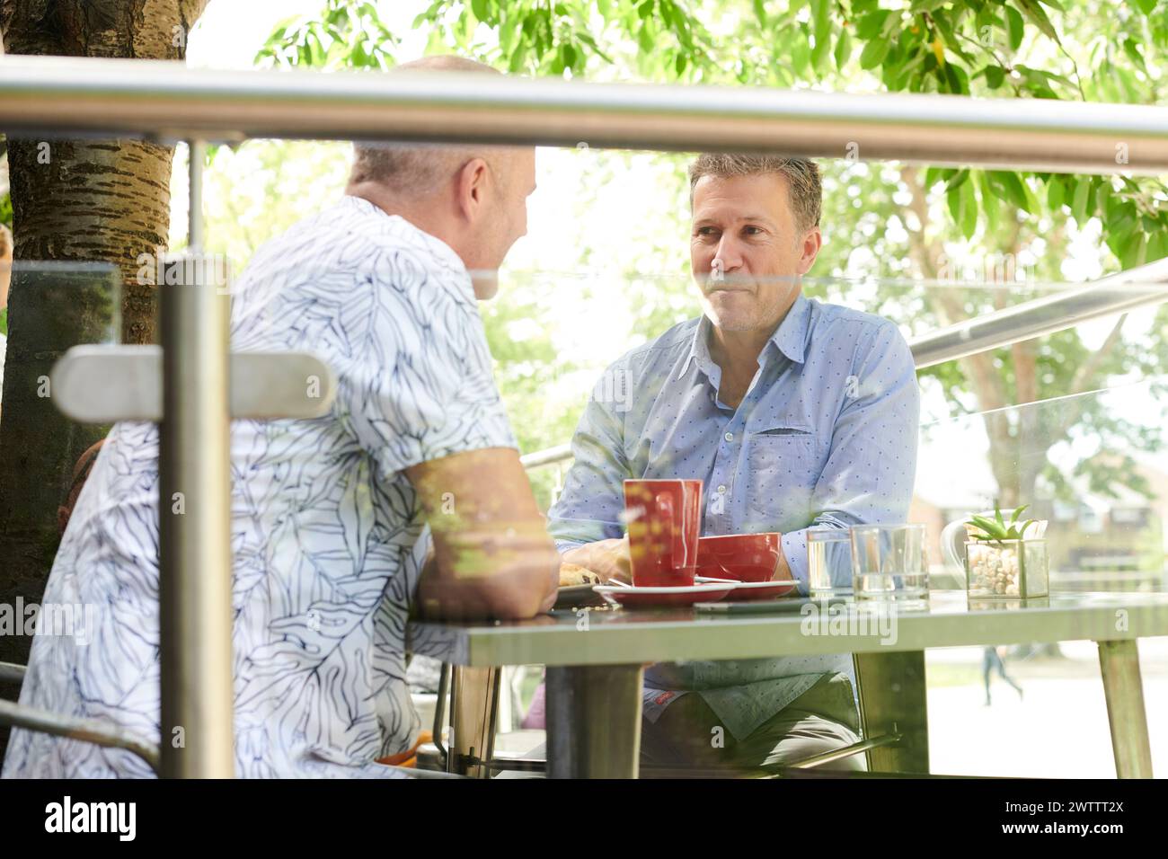 Zwei Männer unterhalten sich an einem Café-Tisch. Stockfoto