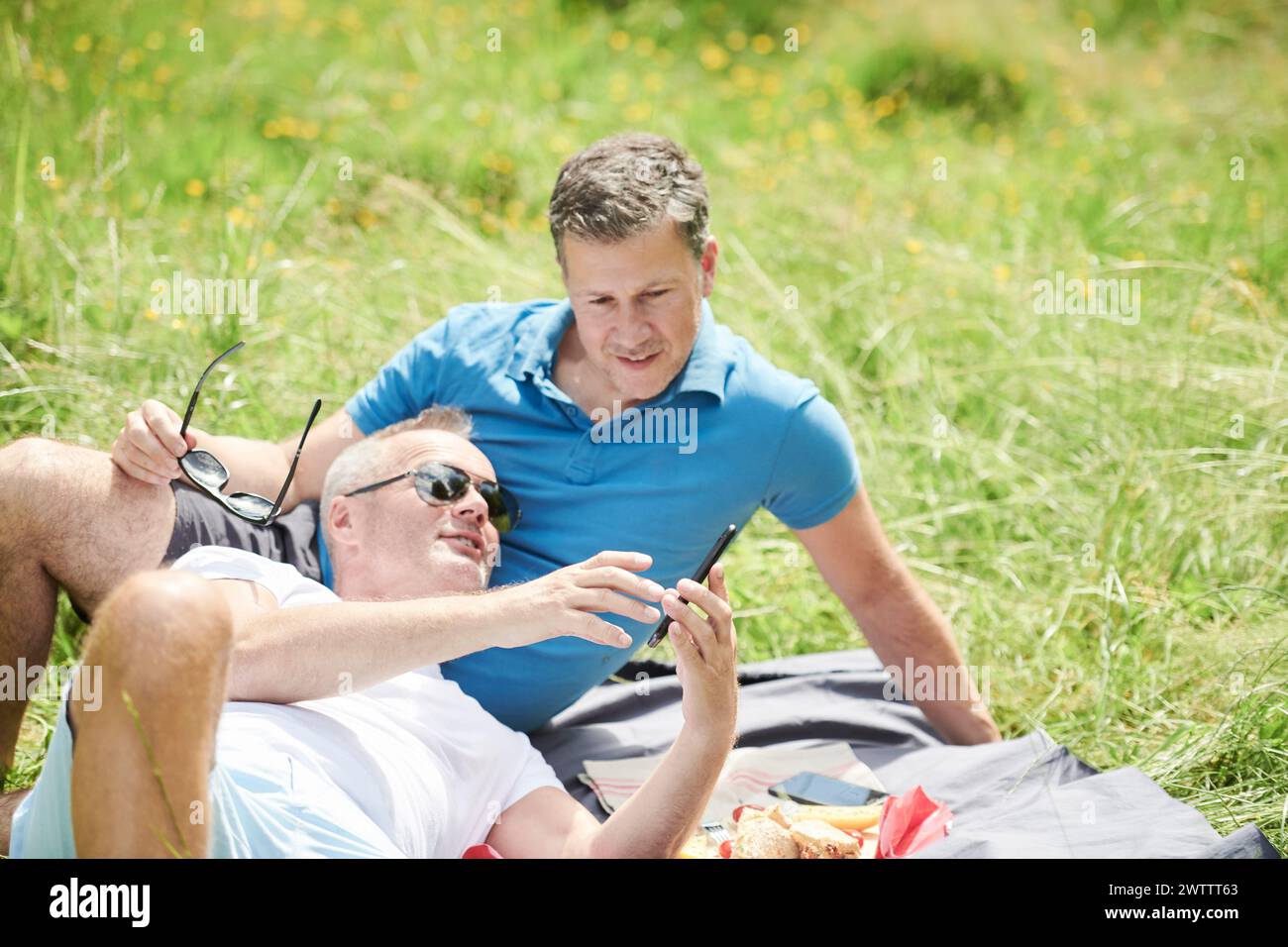 Zwei Männer genießen ein Picknick auf einem grasbewachsenen Feld Stockfoto