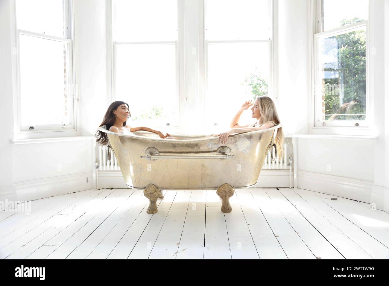 Zwei Frauen unterhalten sich in einer alten Badewanne. Stockfoto