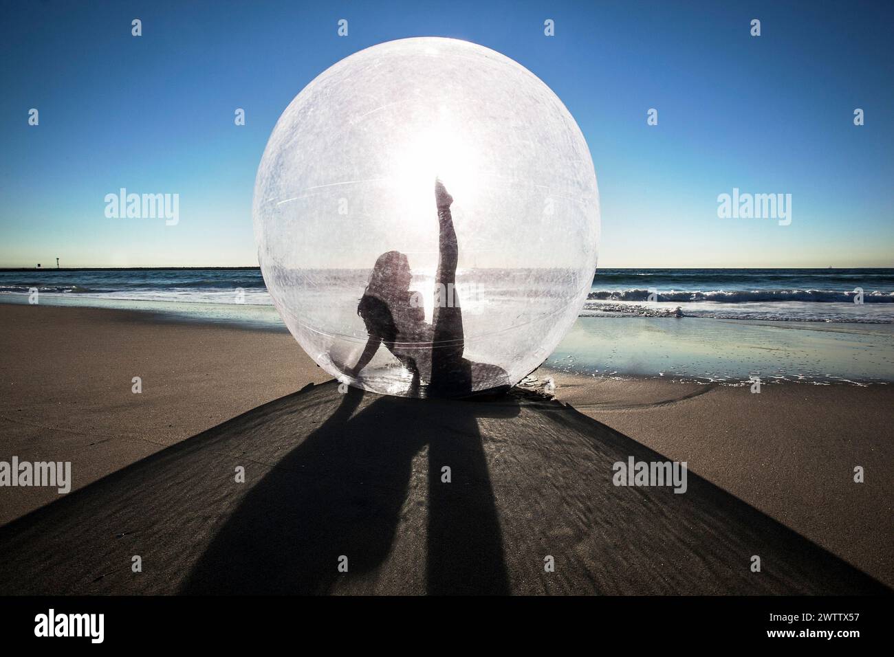 Silhouette einer Person in einer transparenten Kugel am Strand. Stockfoto