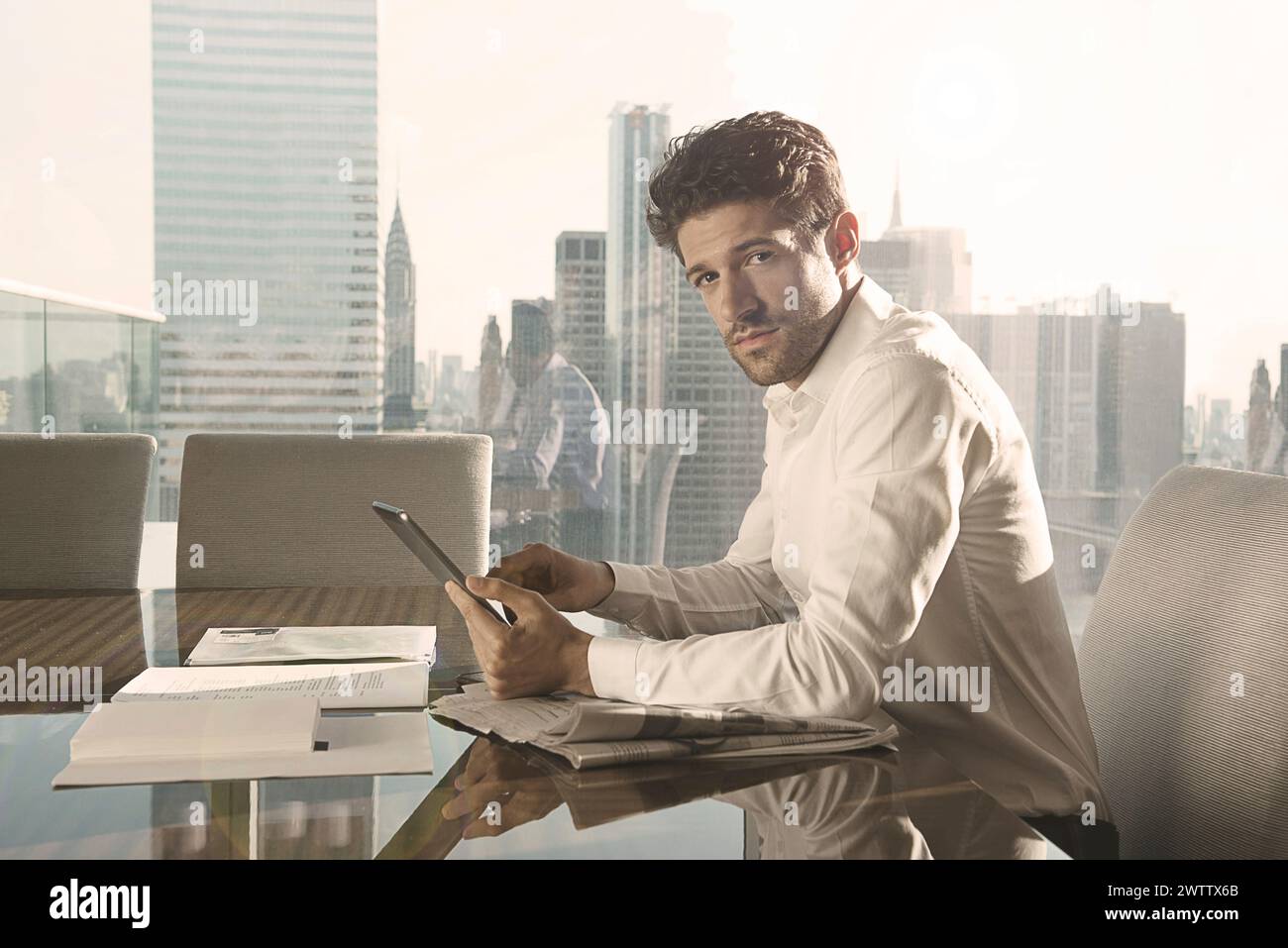 Mann, der im Büro mit Blick auf die Stadt am Tablet arbeitet Stockfoto