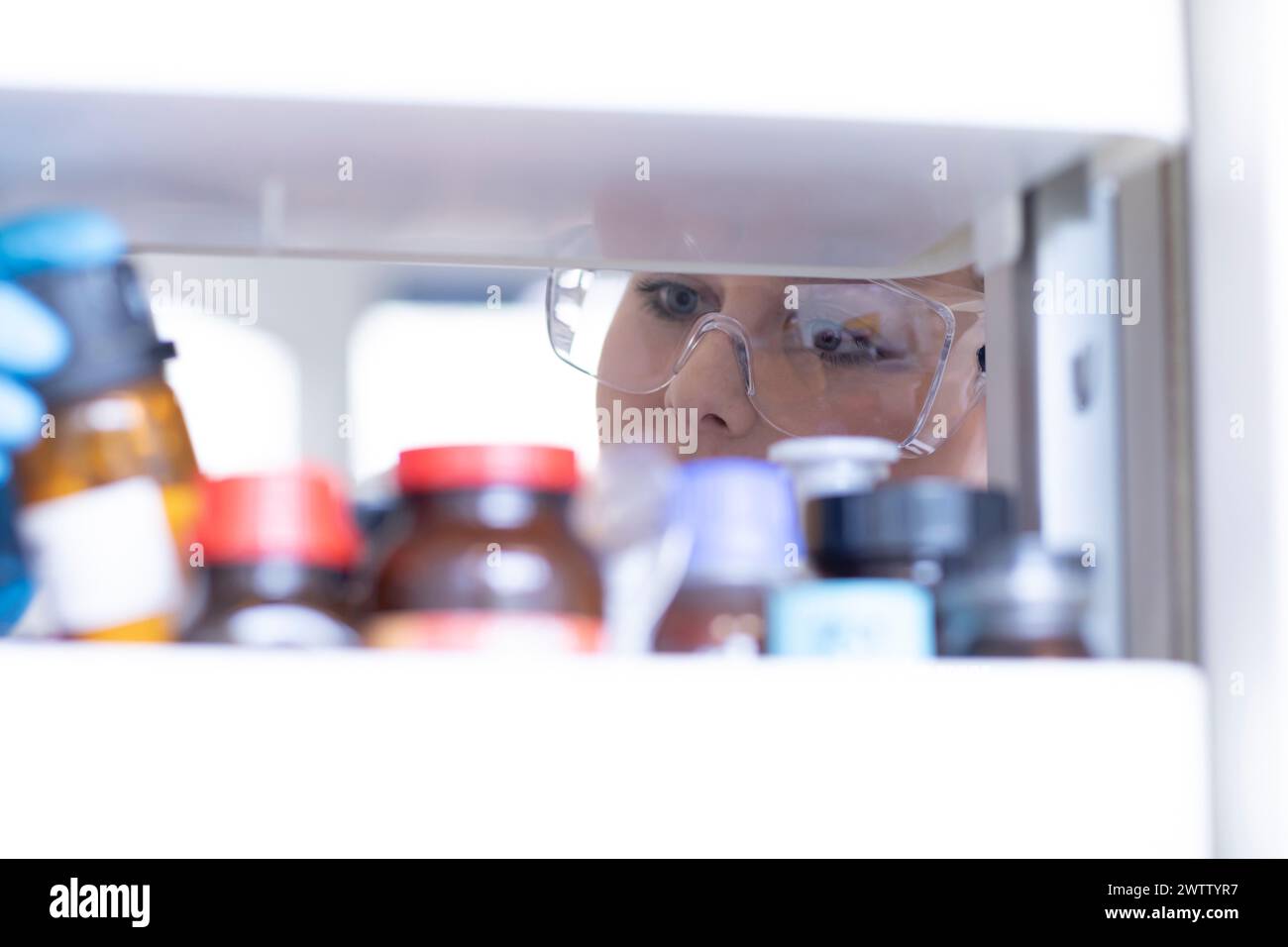 Neugieriger Wissenschaftler, der chemische Proben in einem Laborkühlschrank ansieht Stockfoto