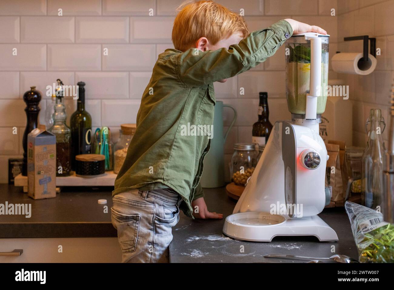 Kleines Kind, das mit einem Mixer in einer Küche experimentiert Stockfoto