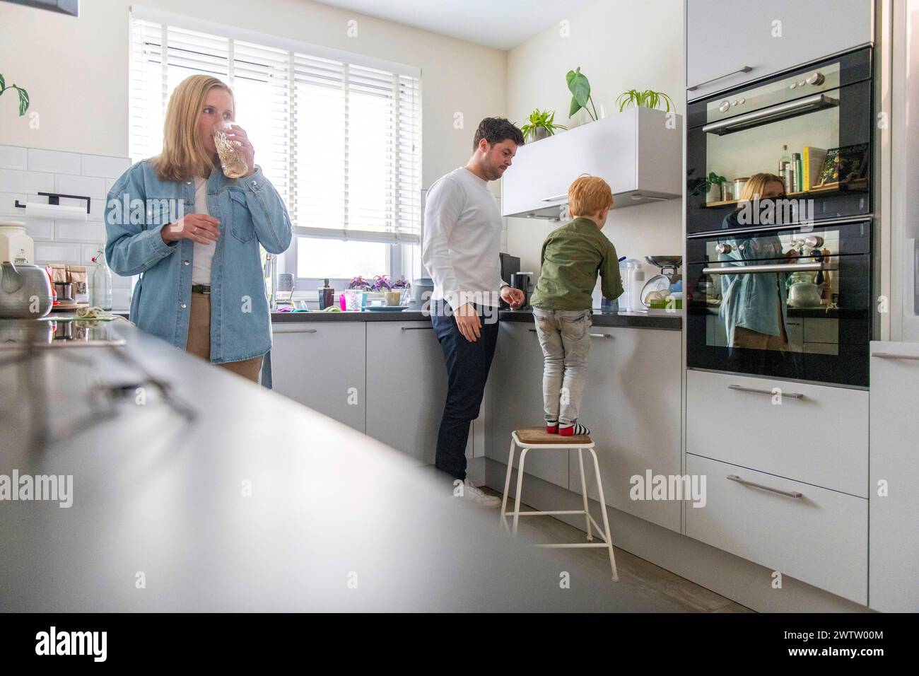 Die Familie genießt die gemeinsame Zeit in einer gemütlichen, sonnendurchfluteten Küche Stockfoto
