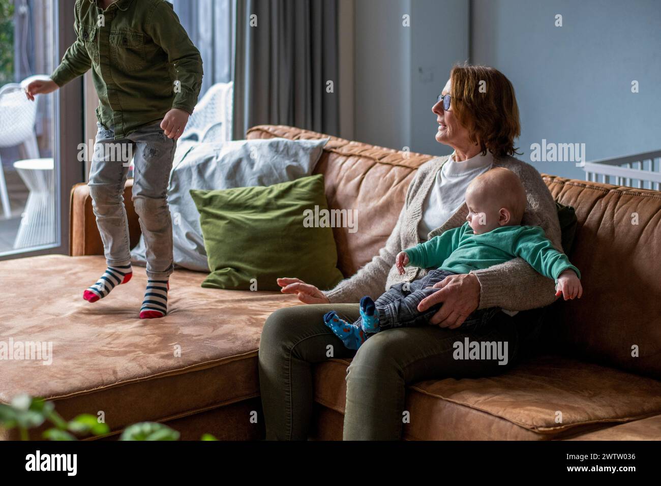 Familienzeit auf einem gemütlichen Sofa mit verspielten Momenten in einem hellen Wohnzimmer. Stockfoto