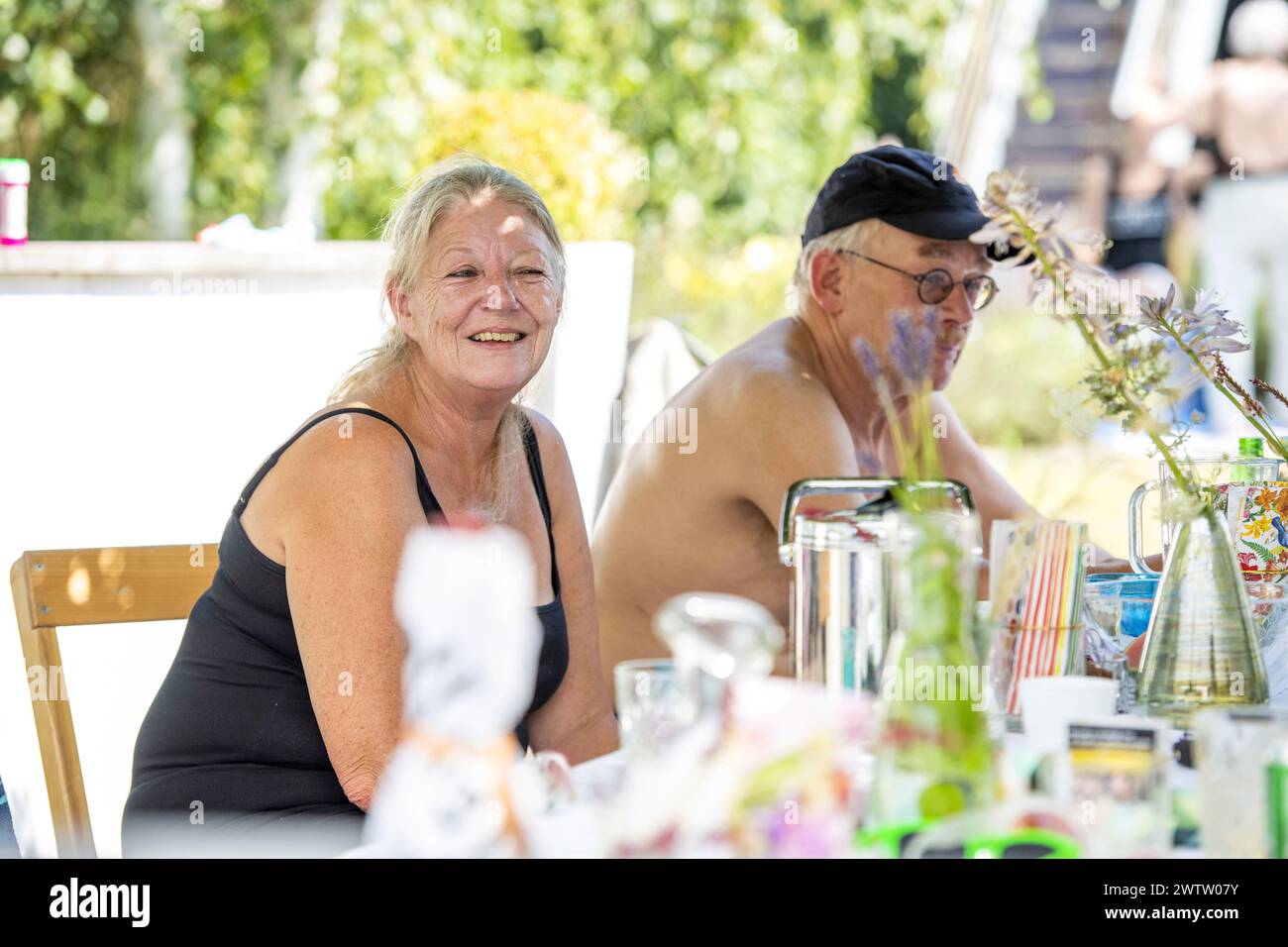Ein älteres Paar lächelt draußen an einem Tisch Stockfoto