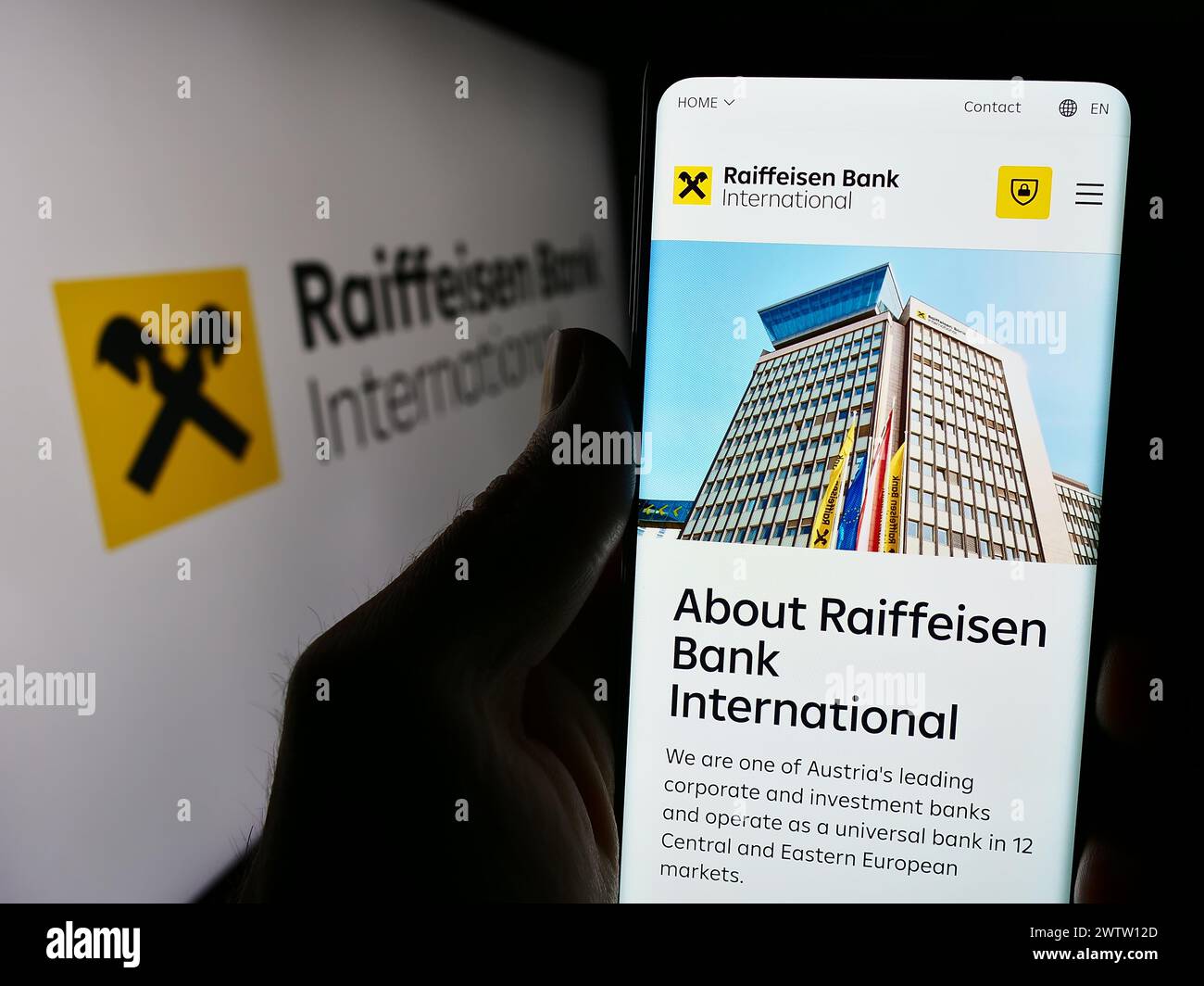 Handybesitzer mit Webseite der österreichischen Raiffeisen Bank International AG (RBI) mit Logo. Konzentrieren Sie sich auf die Mitte des Telefondisplays. Stockfoto